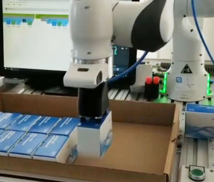 The robot packs small product packages into a larger package.